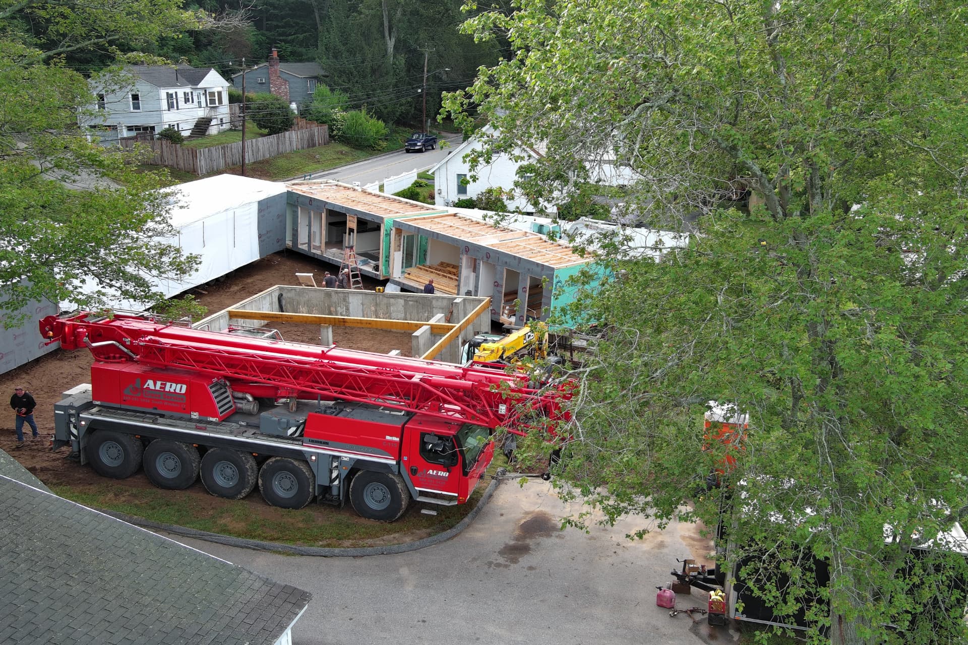 Aerial view of an Aero crane and modular home delivery trailers at a Connecticut modular home build