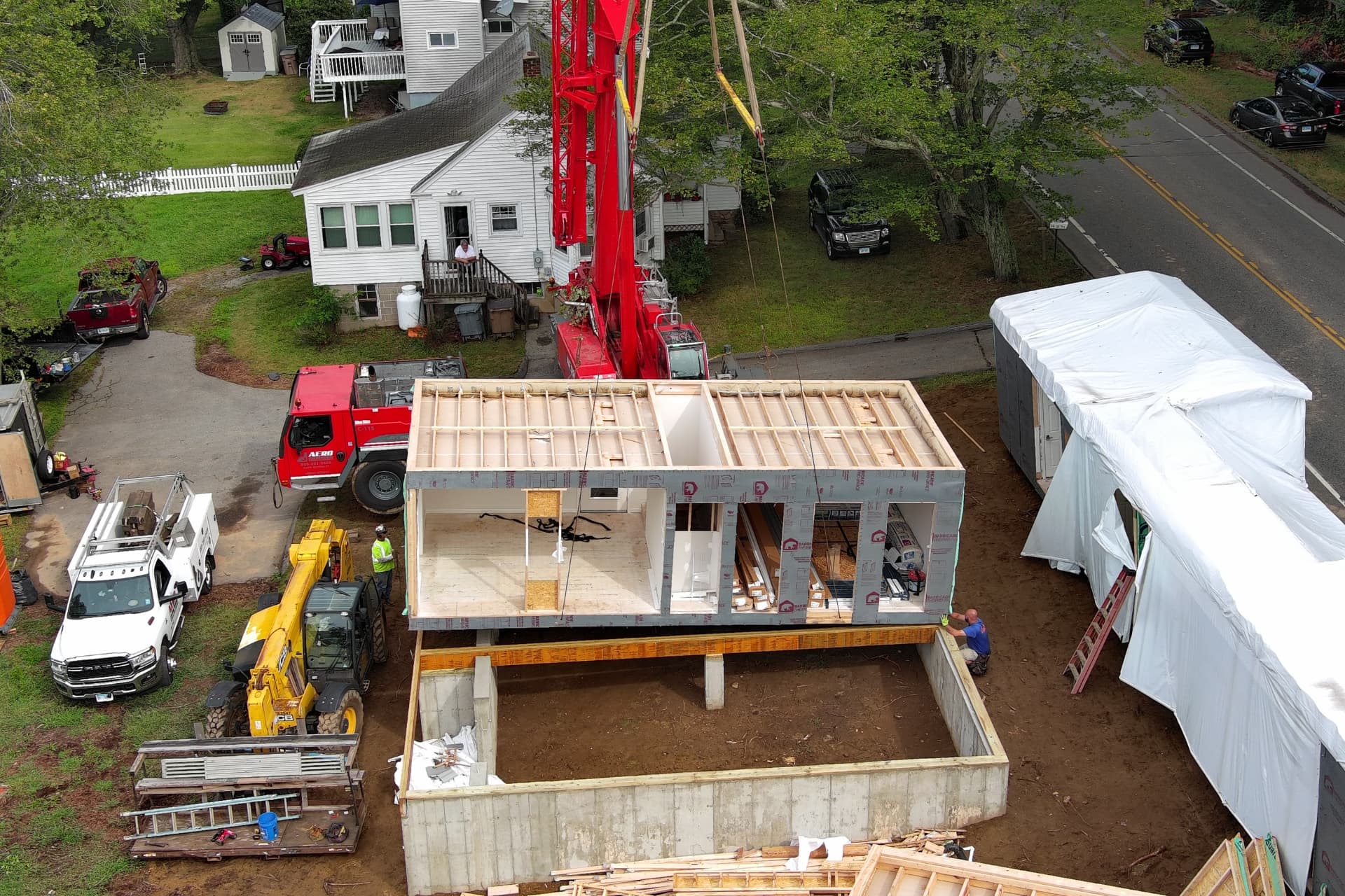 Drone photo of a modular home box suspended over a basement foundation on a Connecticut job site