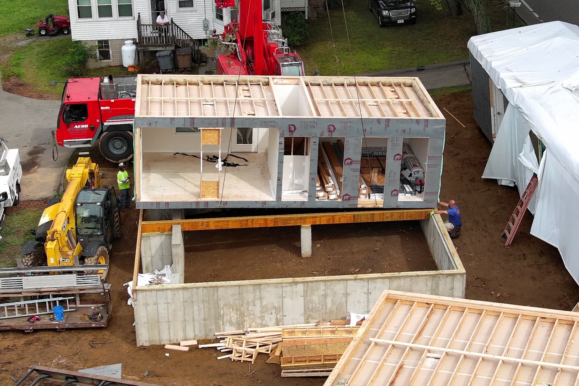 Crane lowering a modular home module onto a poured concrete foundation in Wethersfield, Connecticut